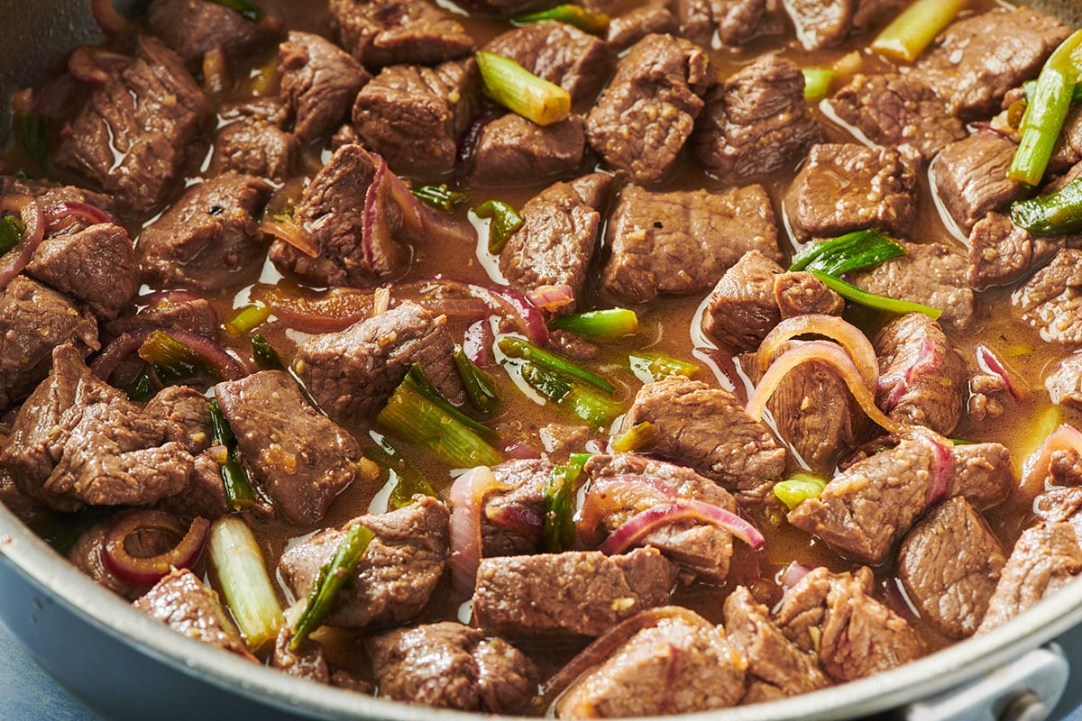 Shaking beef stir-fry in pan.