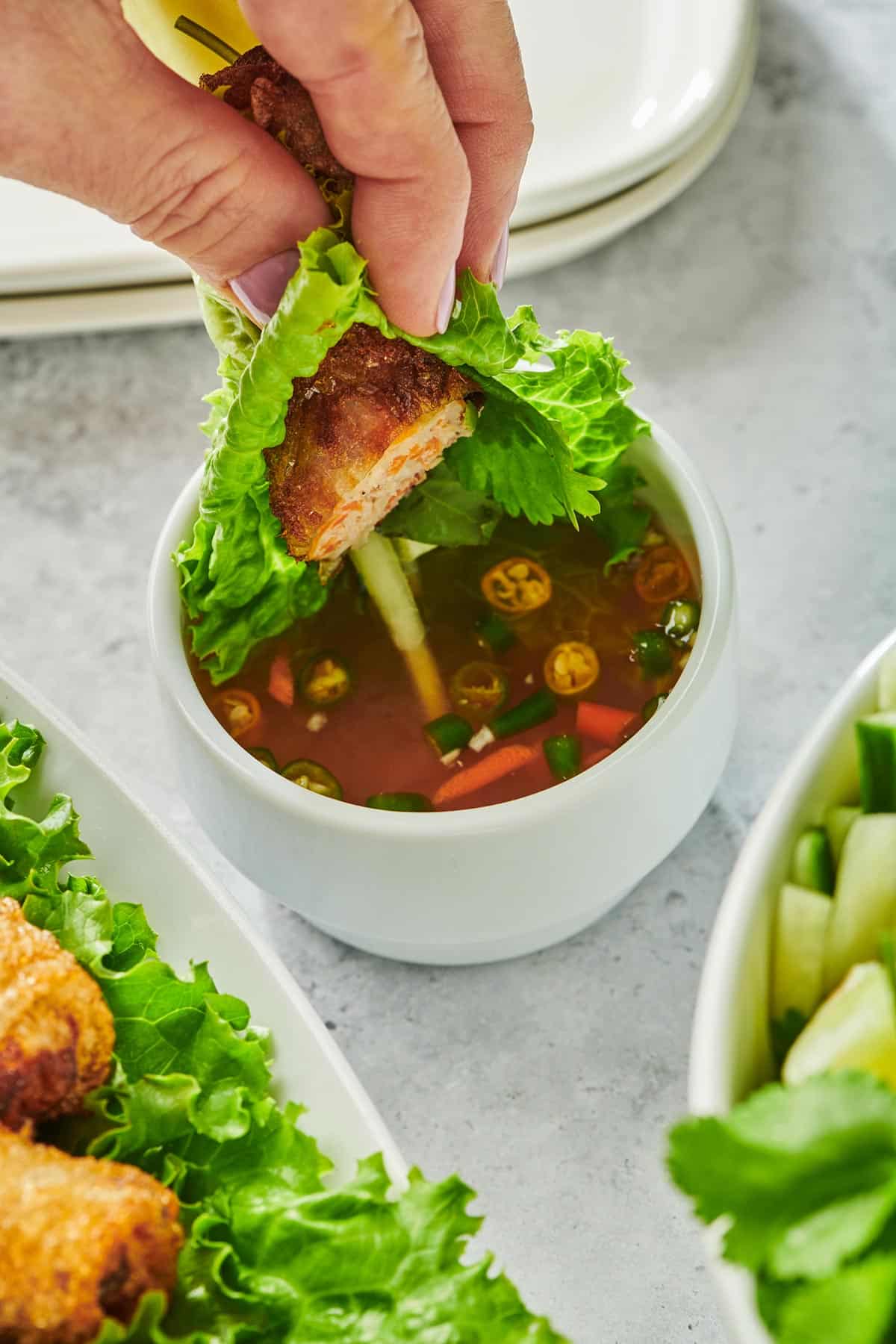 Woman dipping Vietnamese Spring Rolls in nuoc mam sauce.