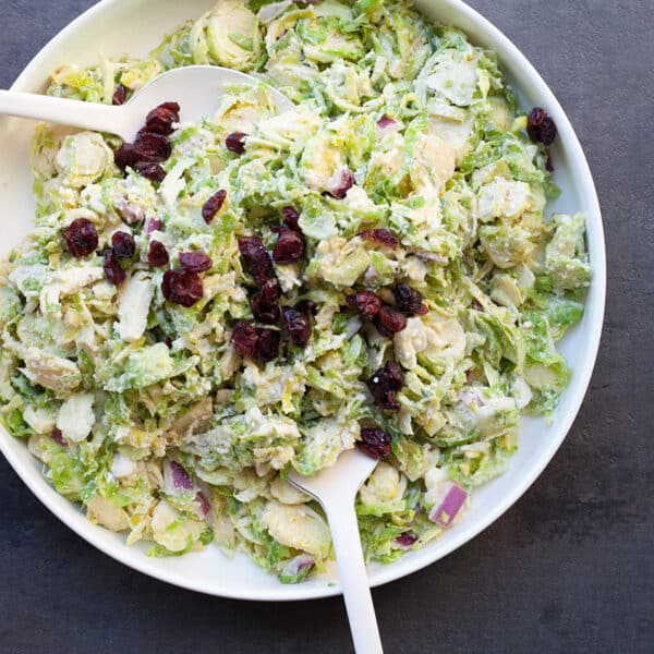 Brussels sprouts coleslaw in bowl topped with dried cherries.