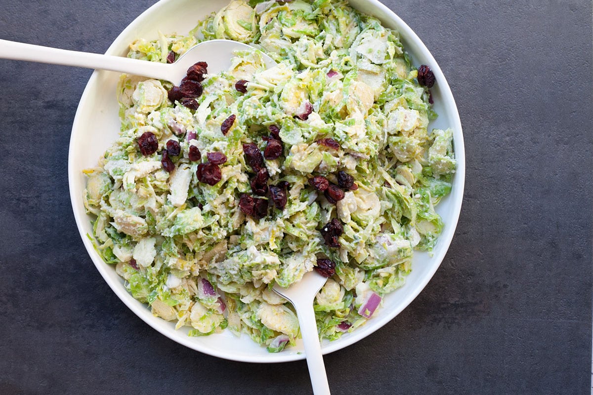 Brussels sprouts coleslaw in bowl topped with dried cherries.