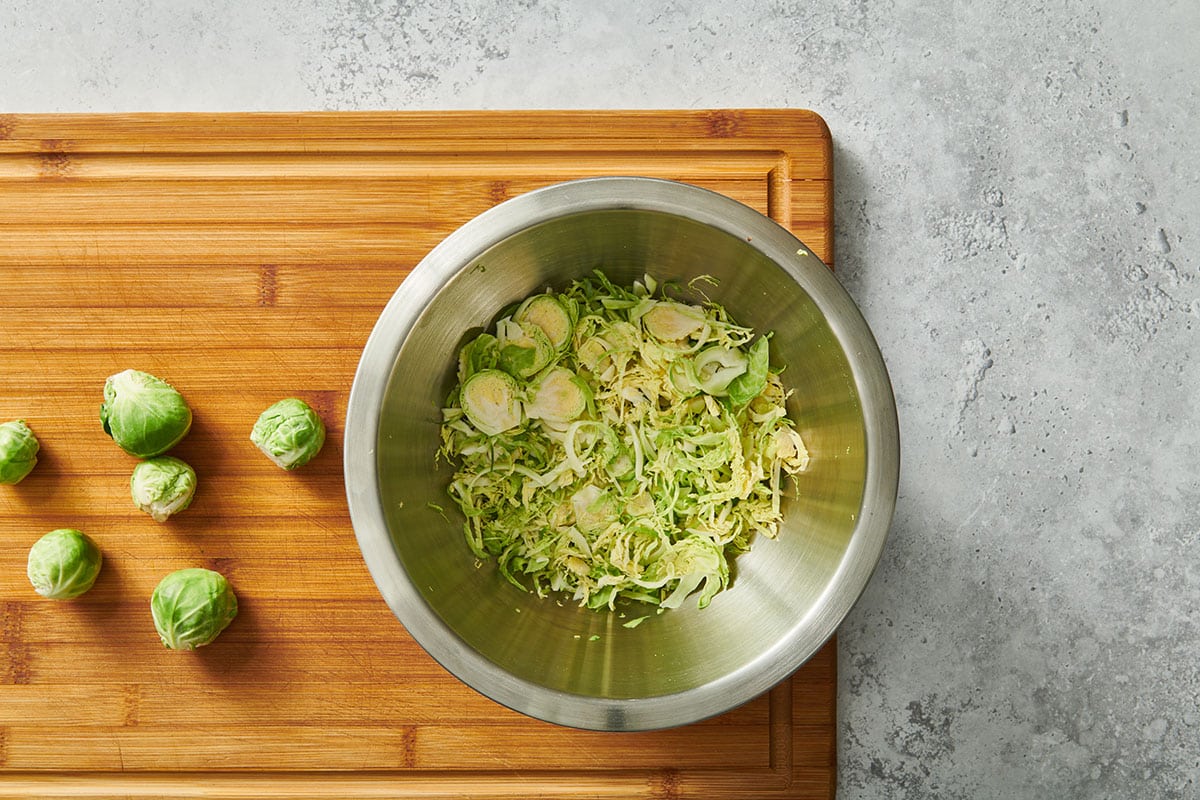 Bowl of shredded Brussels sprouts on cutting board.
