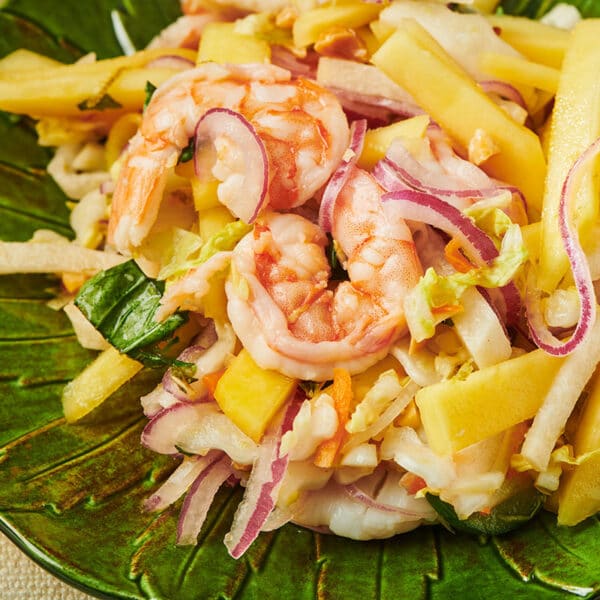 Vietnamese Green Mango Salad with shrimp on green plate.