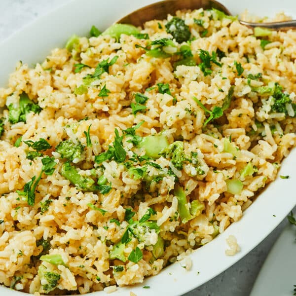 Cheesy rice with broccoli in serving dish with spoon.