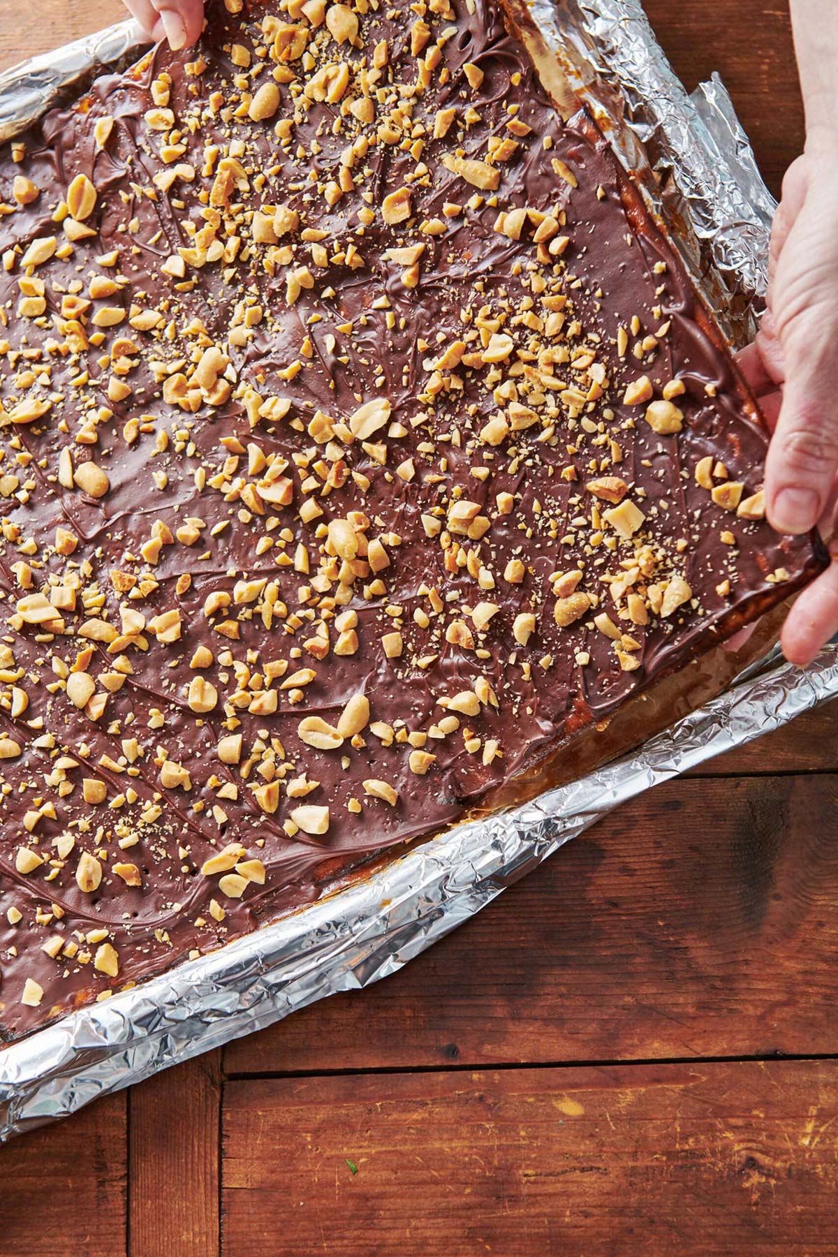 Woman pulling up the corner of a sheet of Chocolate Covered Caramel Matzoh.