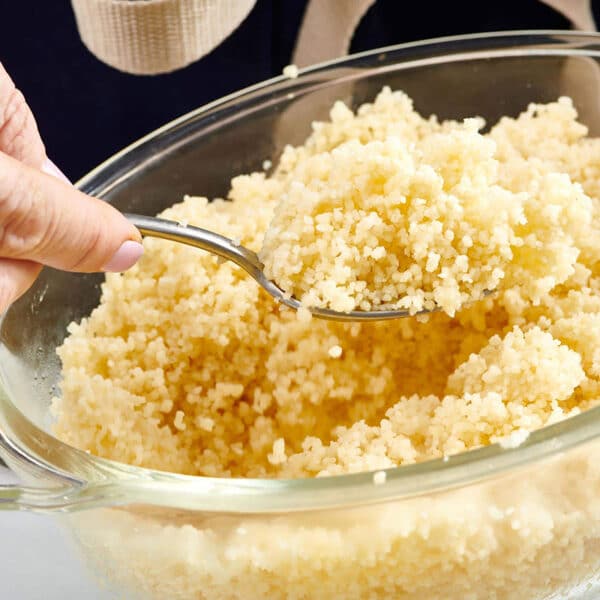 Fluffing cooked millet with fork in bowl.