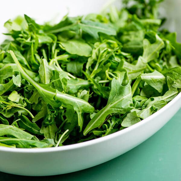 White bowl filled with fresh arugula.