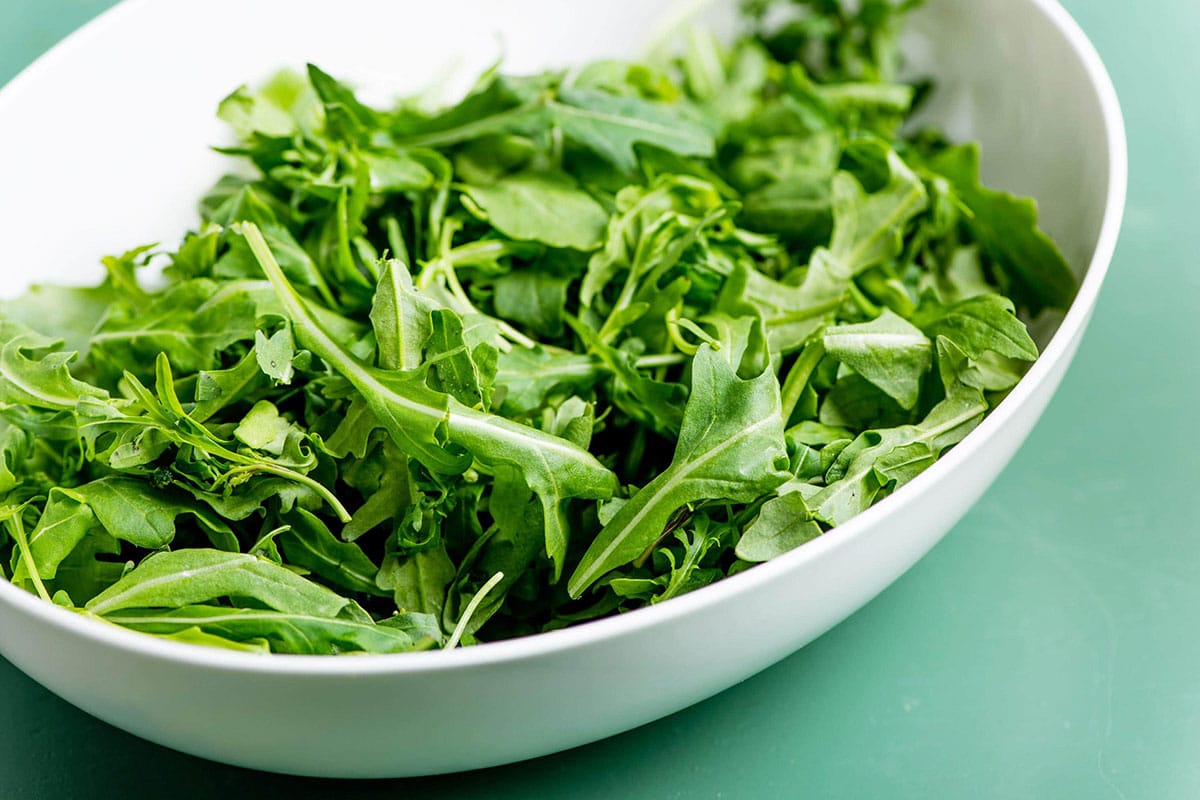 White bowl filled with fresh arugula.