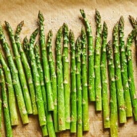 Parchment paper with a line of Roasted Asparagus.