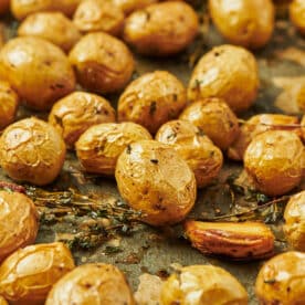 Duck fat roasted potatoes with garlic and thyme on baking sheet.