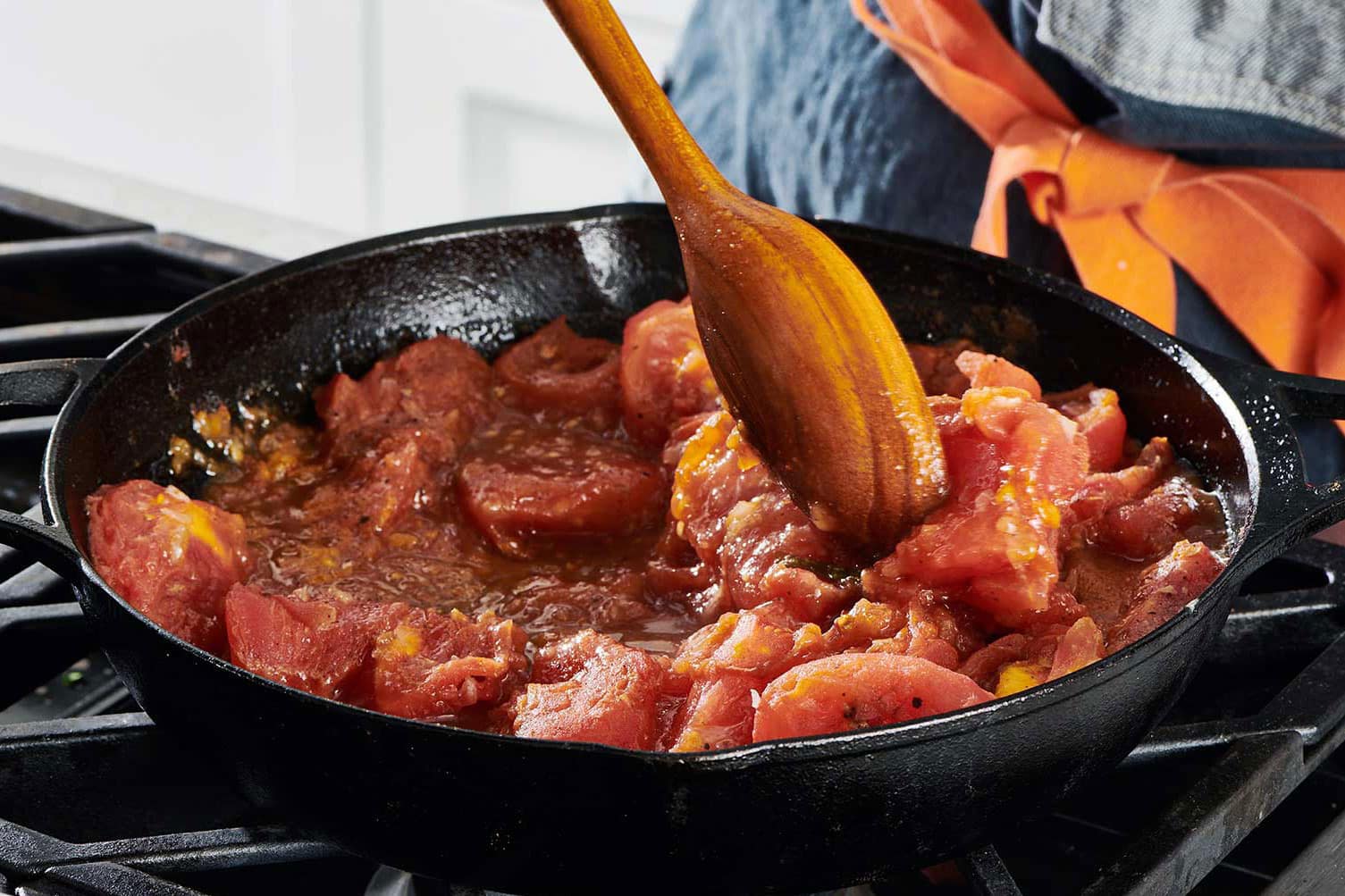 Making Stewed Tomatoes in cast iron pan on stove.