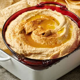 Homemade hummus in bowl with pita chips.
