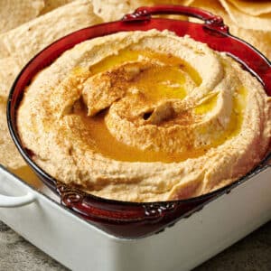 Homemade hummus in bowl with pita chips.