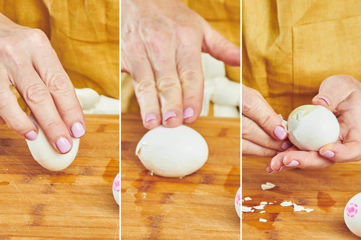 Woman peeling hard-cooked egg on wood cutting board.