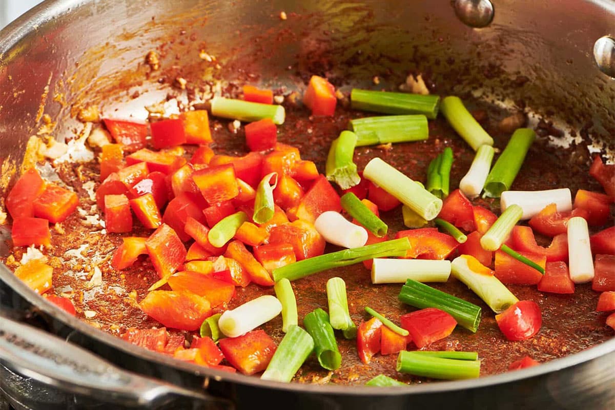 Red peppers and scallions in a skillet.
