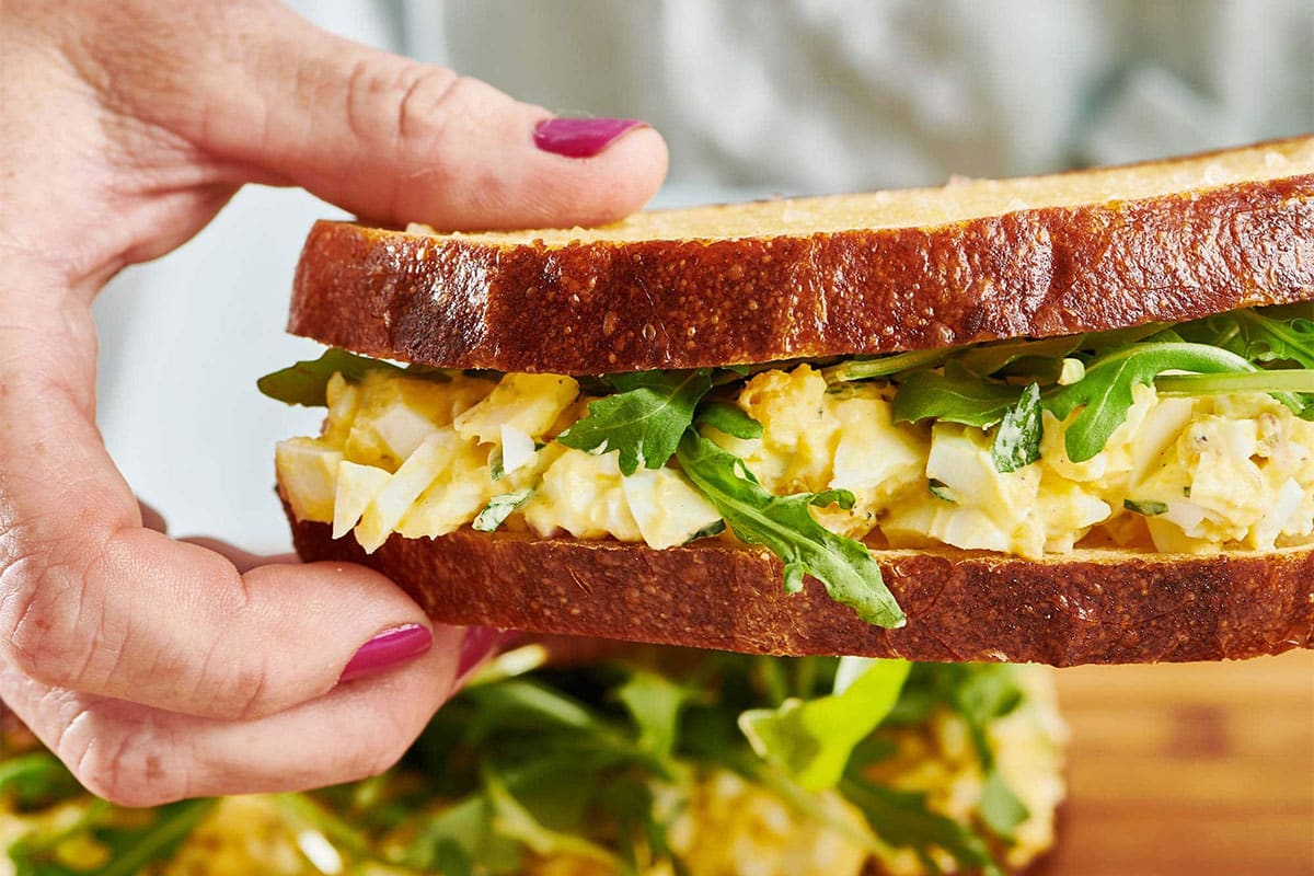 Woman holding an Egg Salad sandwich.