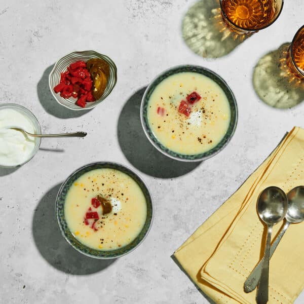 Creamy sweet corn soup in bowls topped with sour cream and peppers.