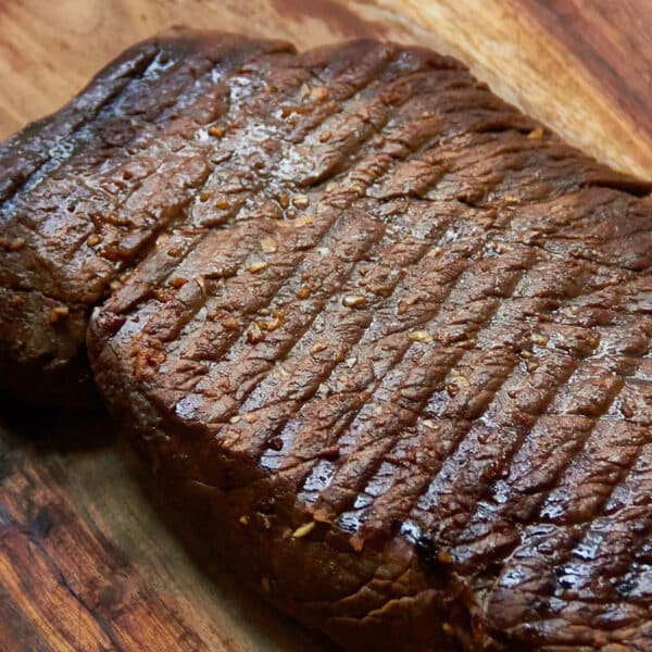 Grilled Marinated London Broil resting on a wooden surface.