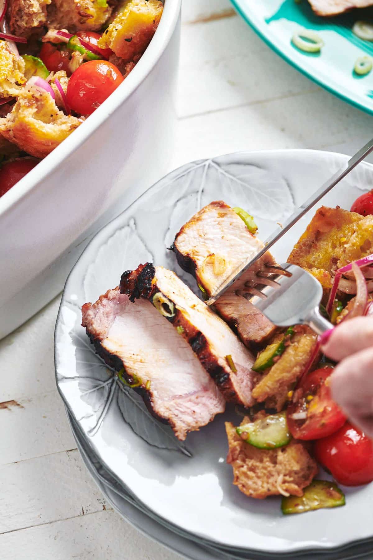 Woman using a fork and knife to cut a Soy-Ginger Pork Chop.