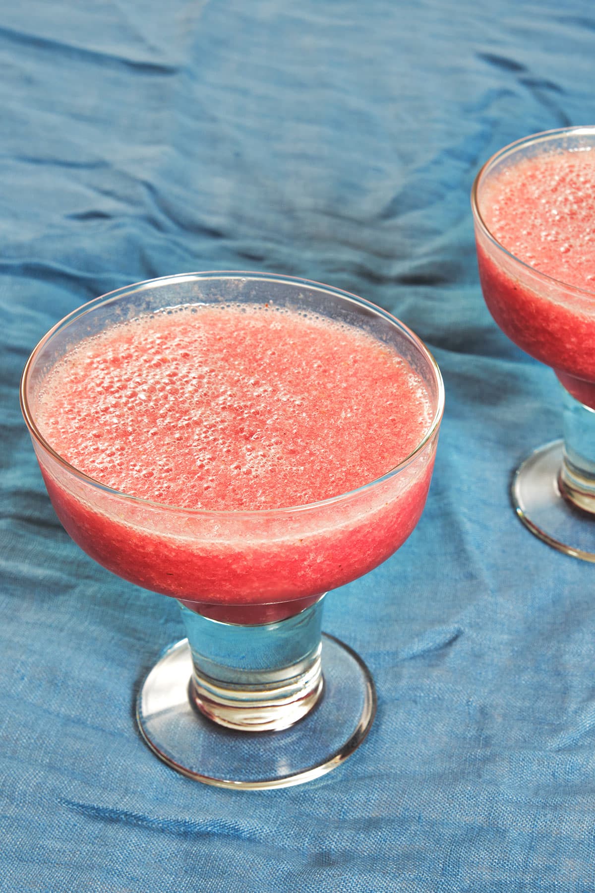 Red frozen cactus pear margaritas on blue table.