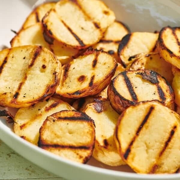 Grilled potato slices in white bowl.