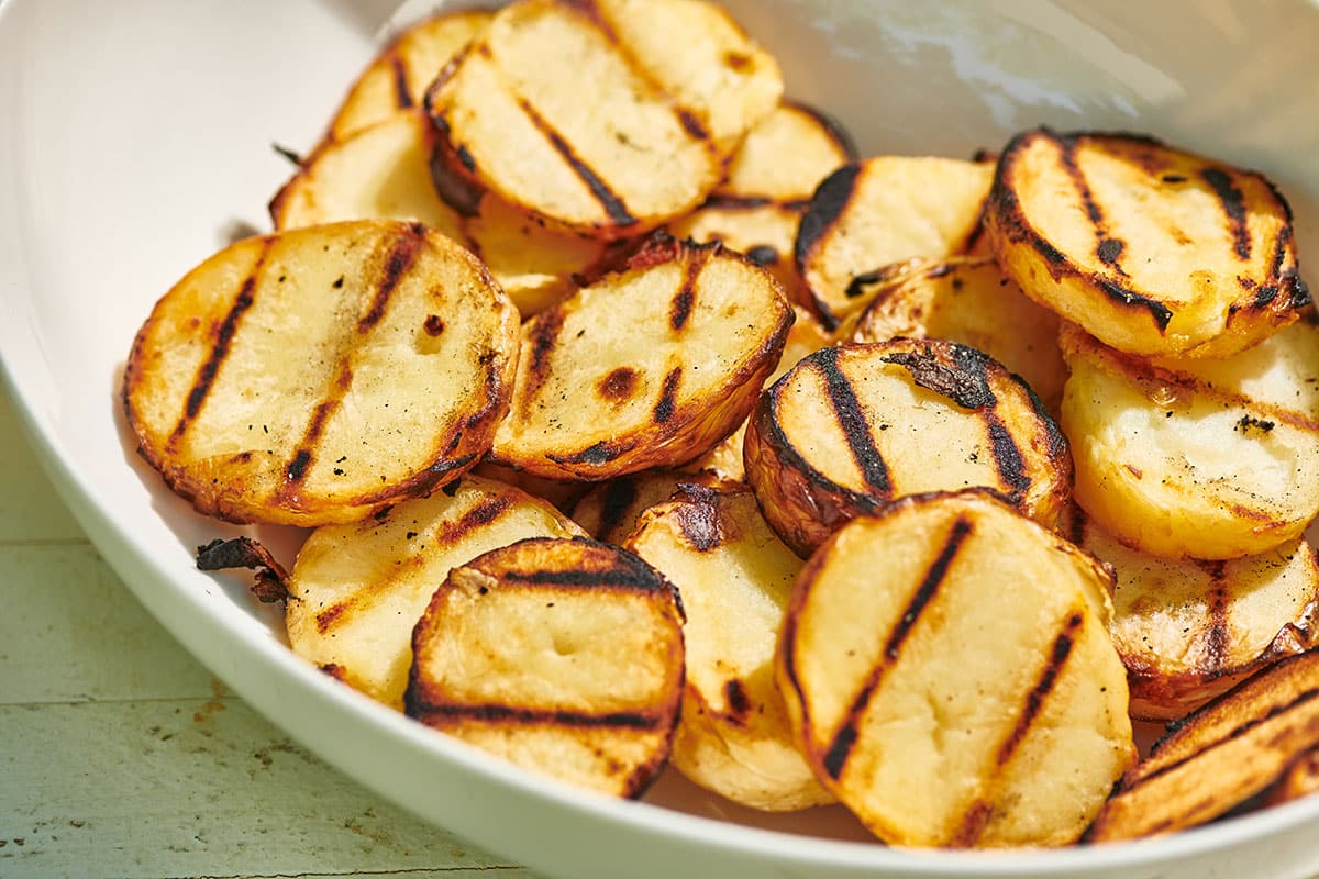 Grilled potato slices in white bowl.