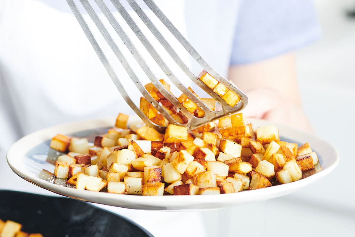 Serving fried potatoes on plate.