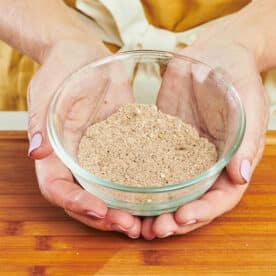 Woman holding small bowl of homemade taco seasoning.