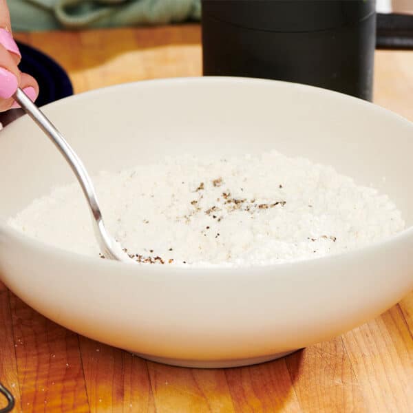 Stirring seasoning into flour in bowl.