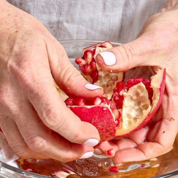 Woman peeling open fresh pomegranate.