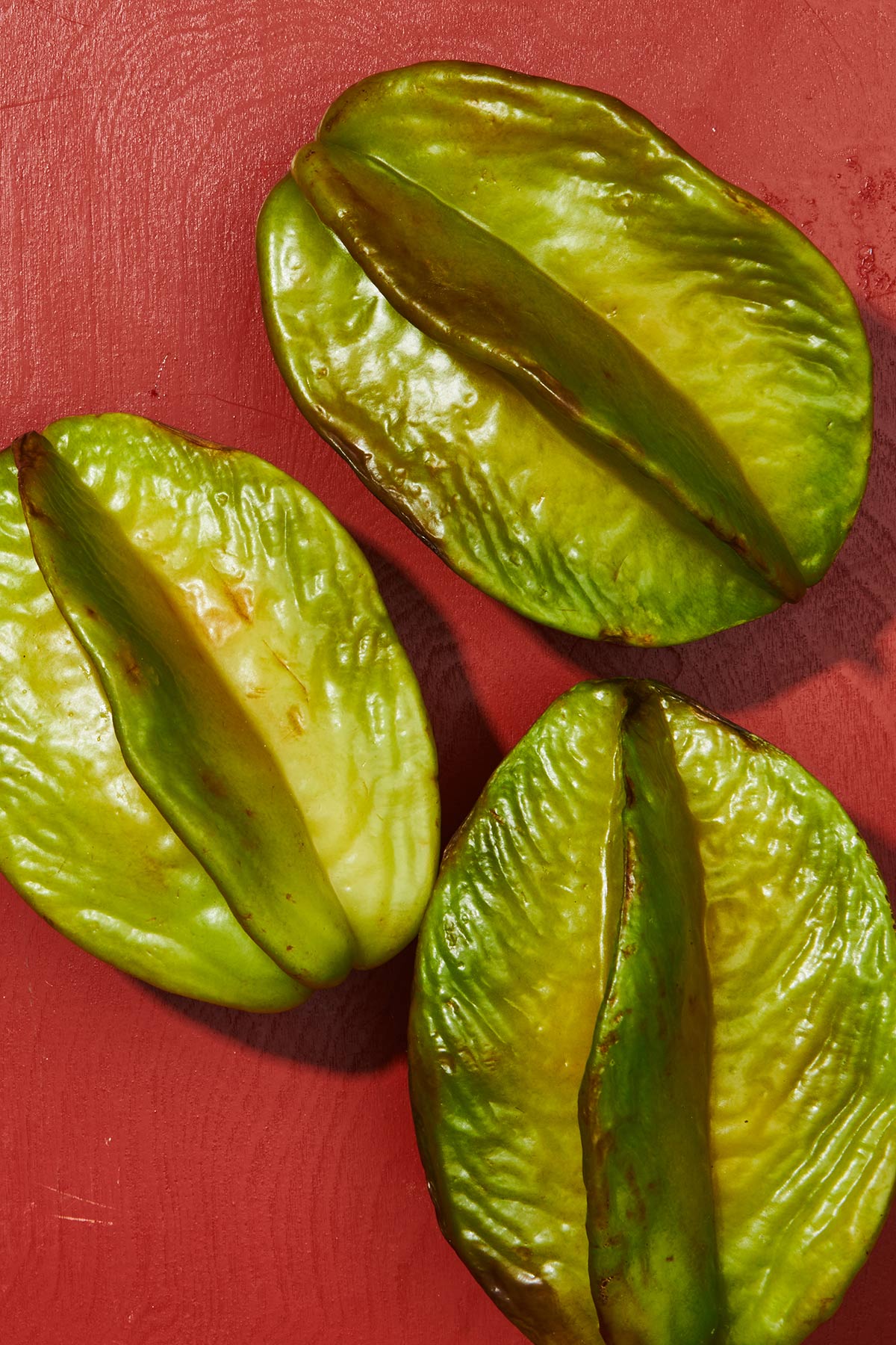 Three whole starfruit on cutting board.