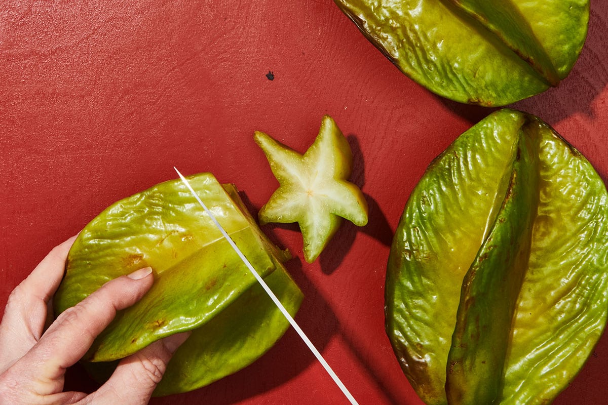 Woman cutting ends off starfruit.