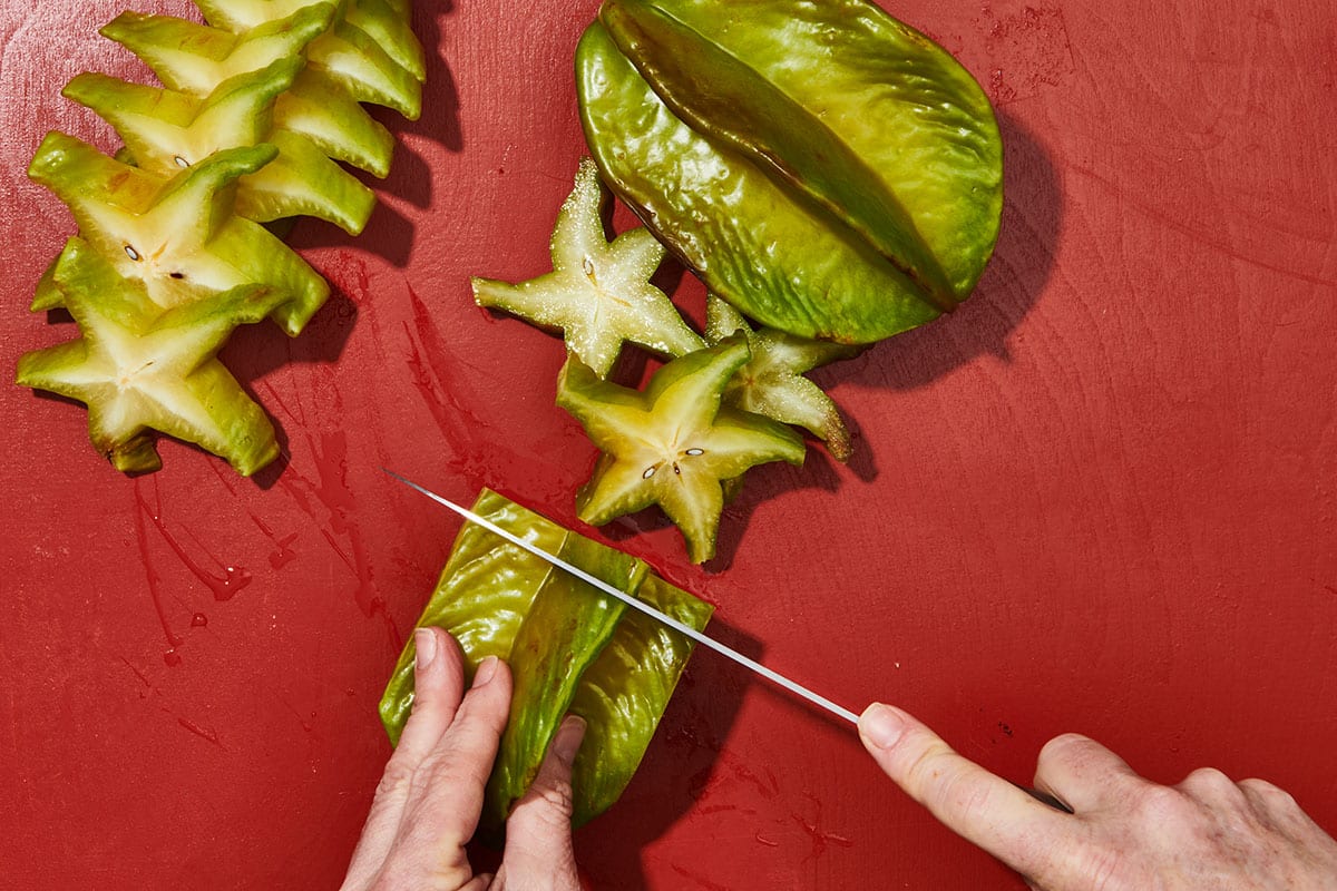 Woman slicing fresh starfruit.