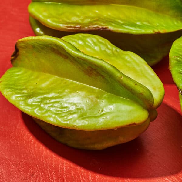 Fresh starfruit on red table.