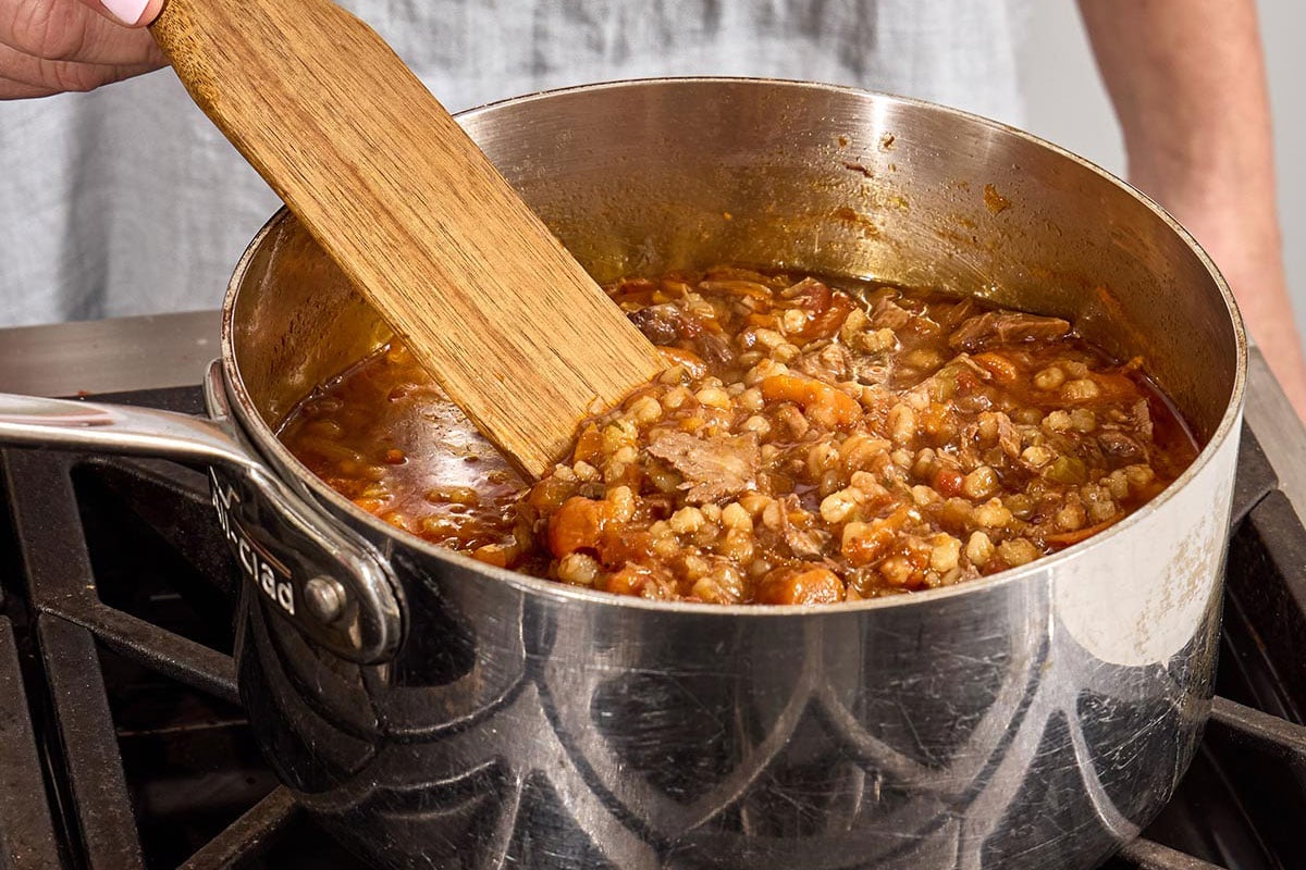 Stirring brisket barley soup with wood spoon.