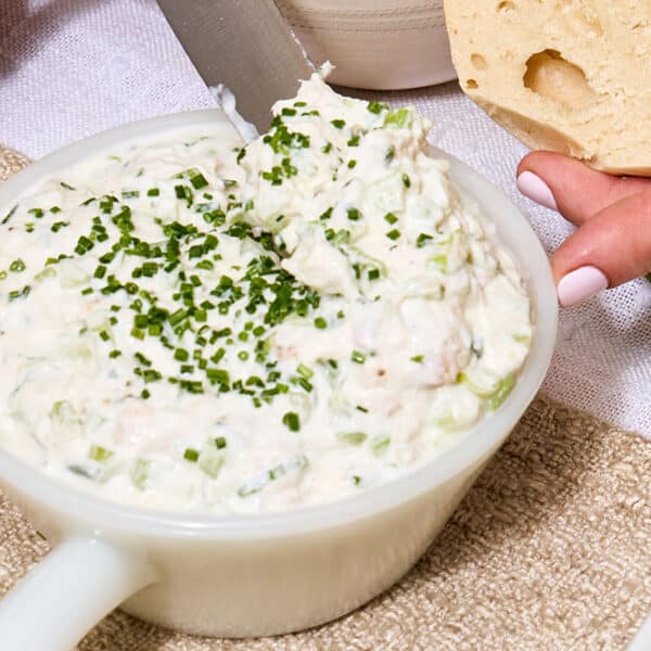 Whitefish salad with chopped chives in bowl on table.