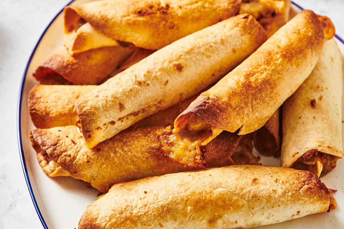 Plate with pile of baked chicken flautas.