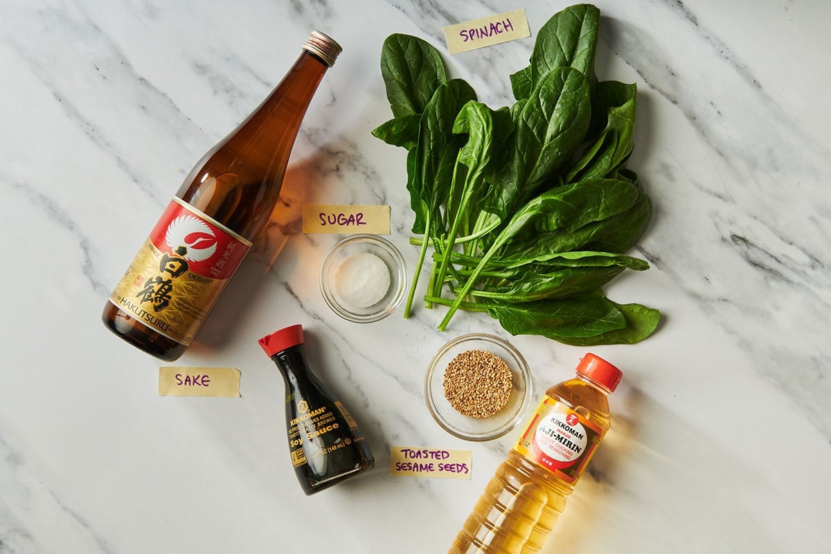 Spinach, mirin, soy sauce, sake, and other ingredients on marble table.