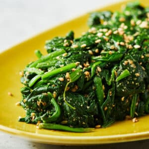 Japanese spinach gomae salad on yellow serving platter.