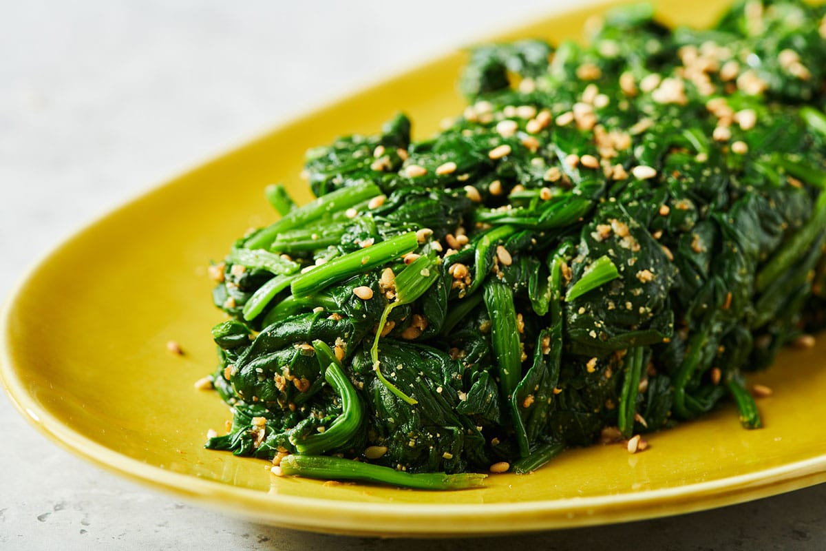 Japanese spinach gomae salad on yellow serving platter.