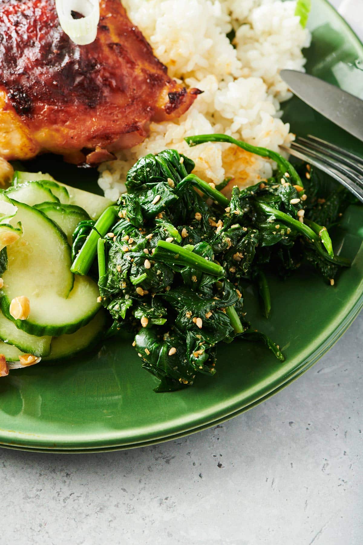 Green plate with Japanese goma-ae salad and other Asian dishes.