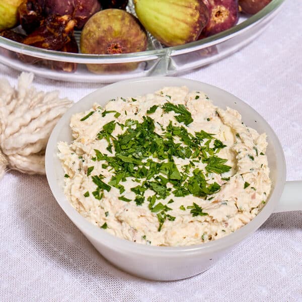 Smoked trout spread in white bowl on table with figs.