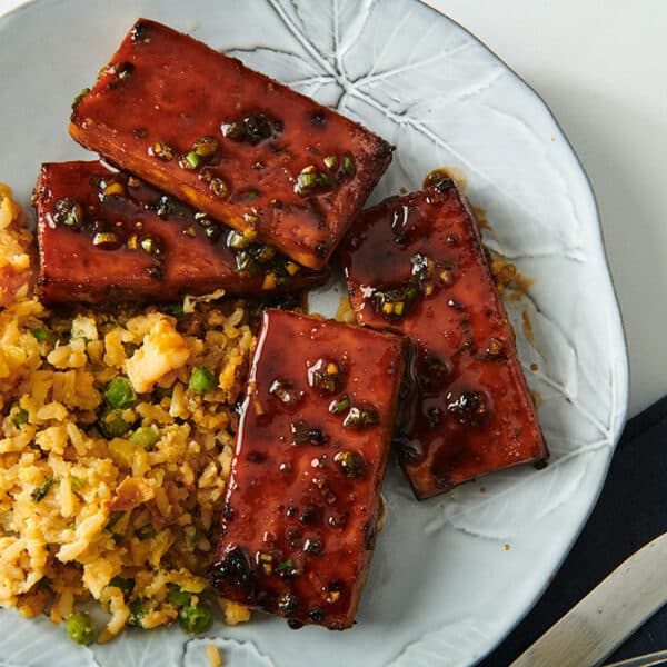 Air-fried tofu with sticky Chinese barbecue sauce on white plate with sides.
