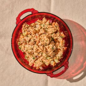 Canned salmon salad in red glass bowl on table.