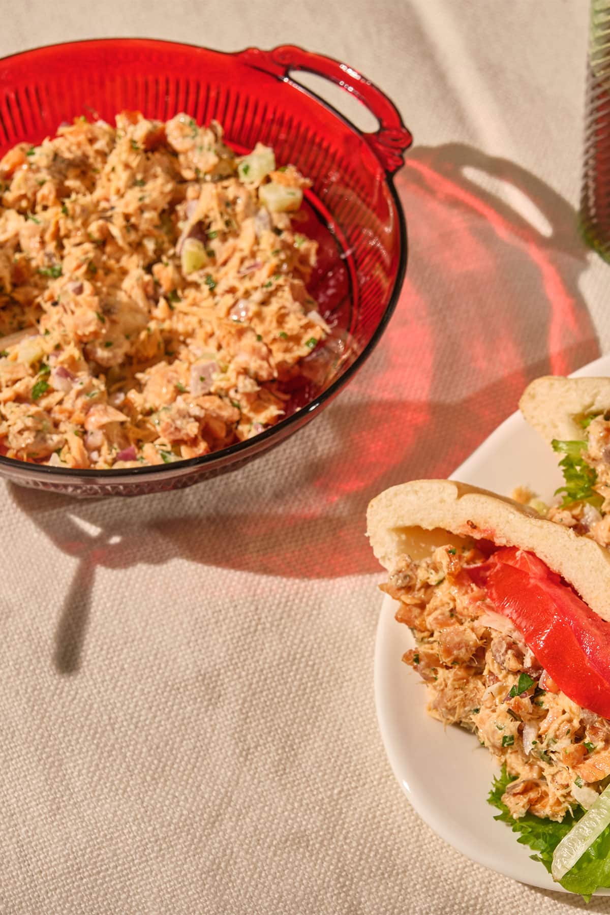 Homemade canned salmon salad in red bowl and in sandwich with lettuce and tomato.