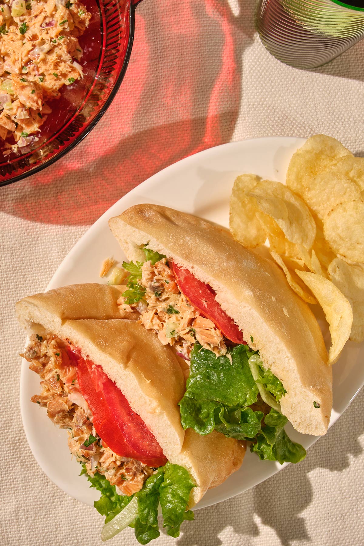 Salmon salad sandwiches with tomatoes and lettuce on plate.