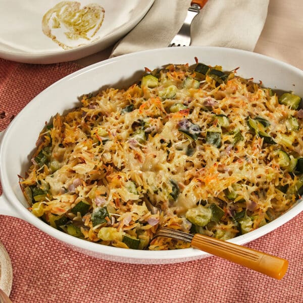 Zucchini casserole with orzo in baking dish on table.