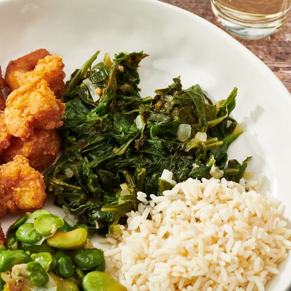 Mustard greens on white plate with rice and other side dishes.