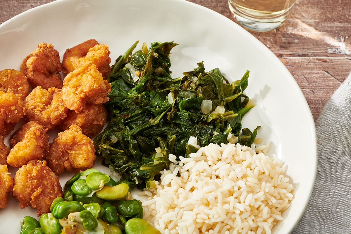 Mustard greens on white plate with rice and other side dishes.