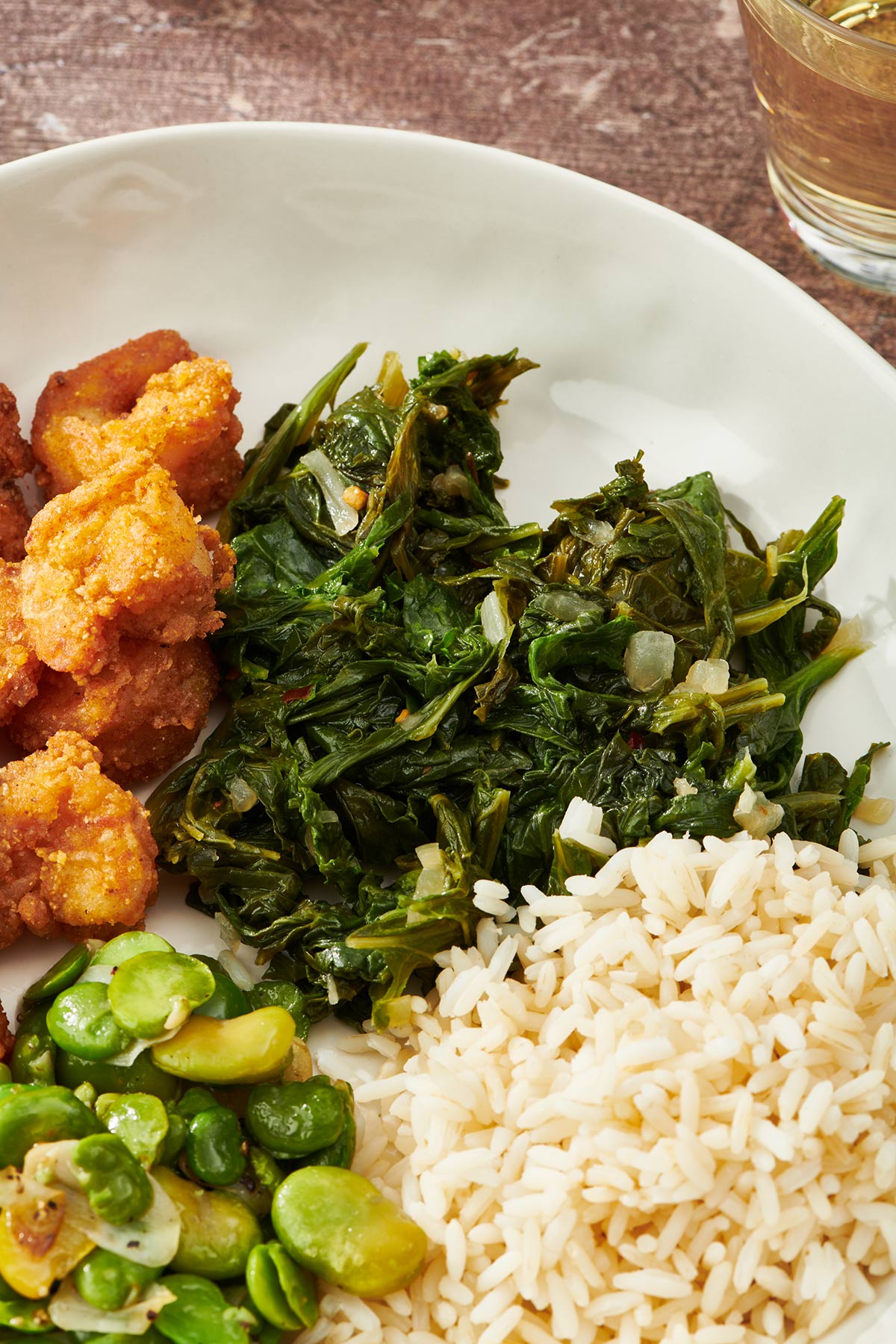 Sauteed Southern mustard greens on plate with rice, fava beans, and other sides.