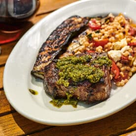 Grilled loin lamb chop on plate with mint and basil pesto and grilled sides.